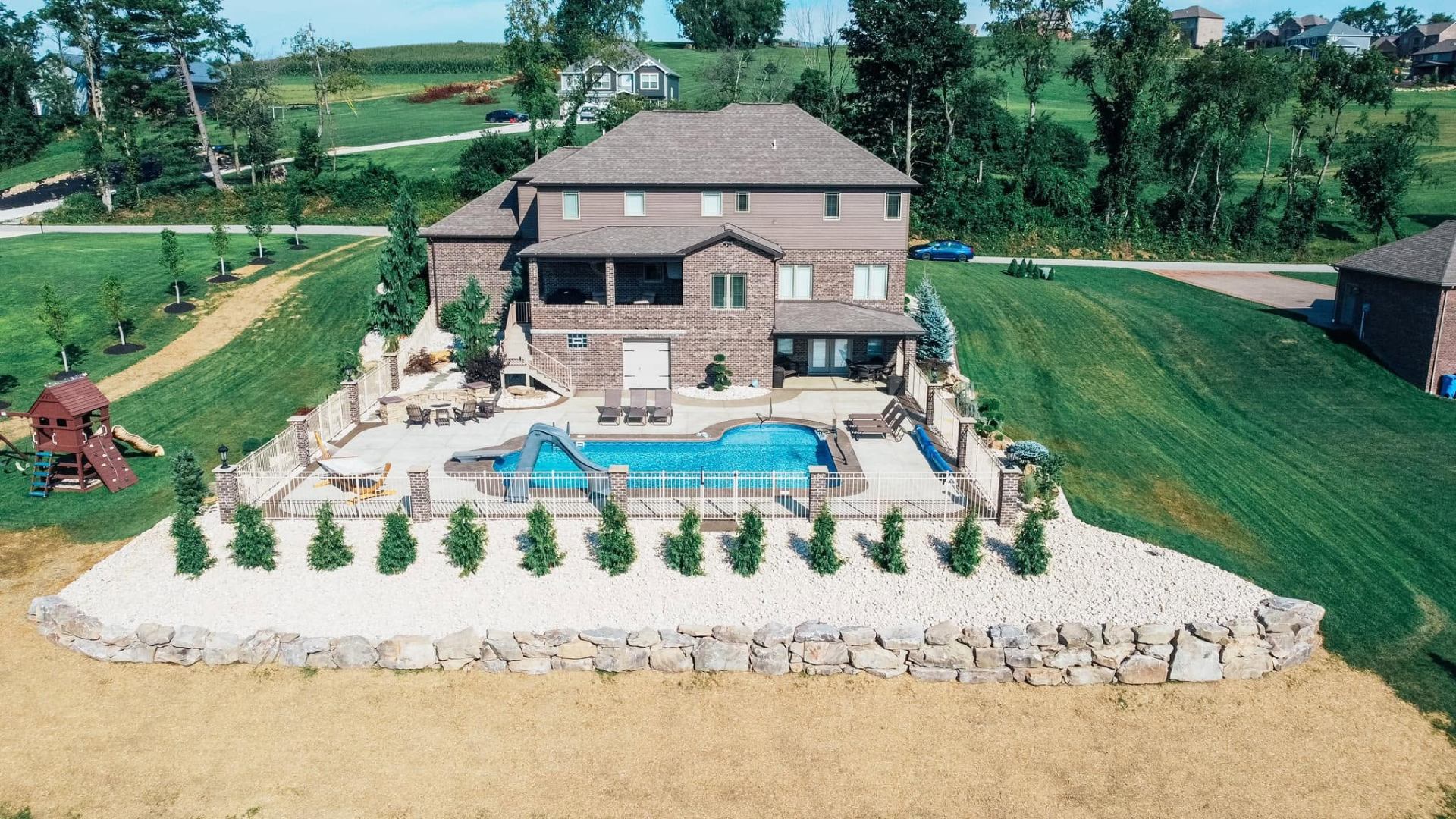 Aerial view of a custom pool, hardscape patio, and natural stone retaining wall in an eastern Pittsburgh suburb