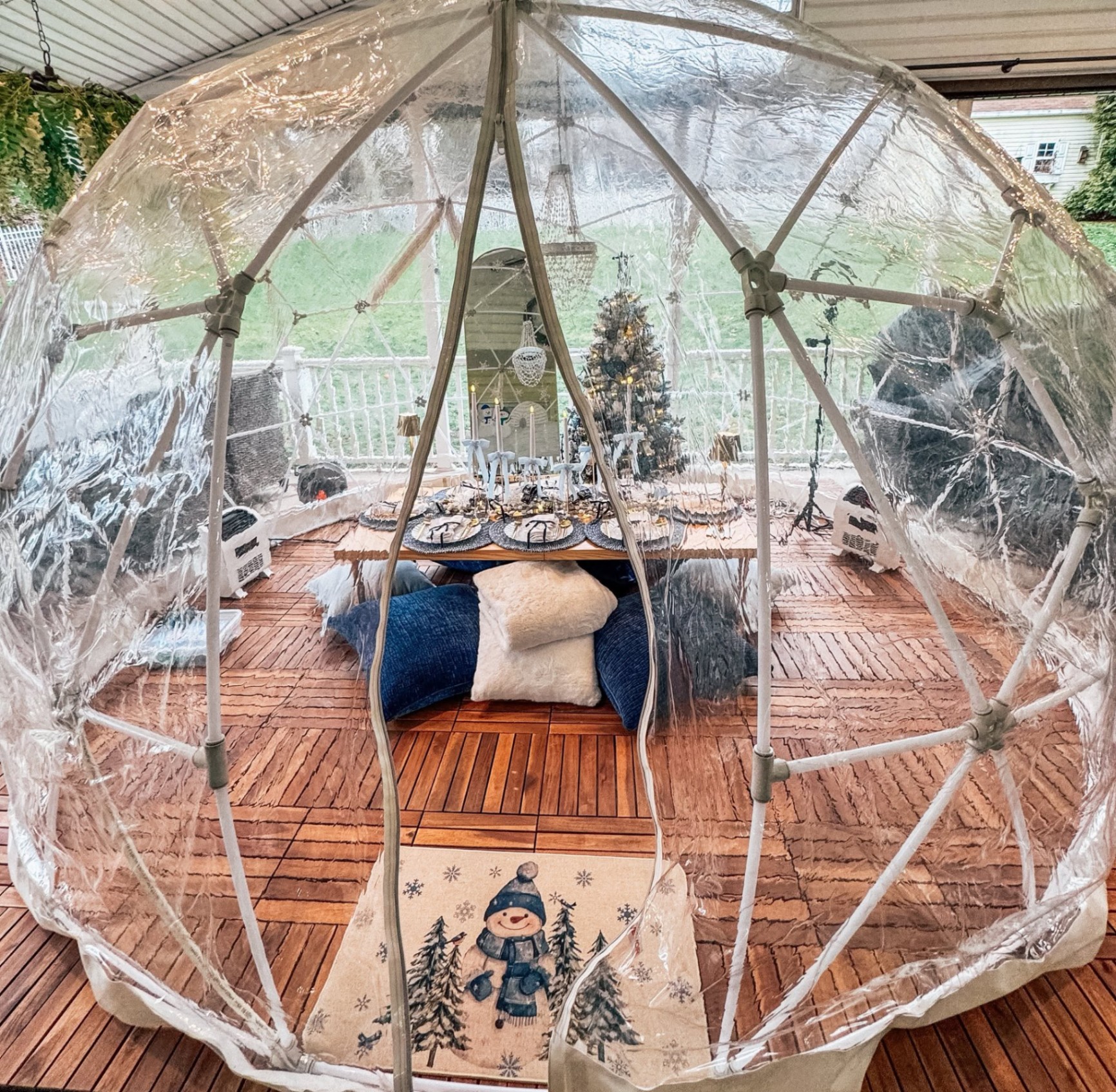 Cozy luxury igloo interior with snowman rug, Christmas tree, and chandelier dining table