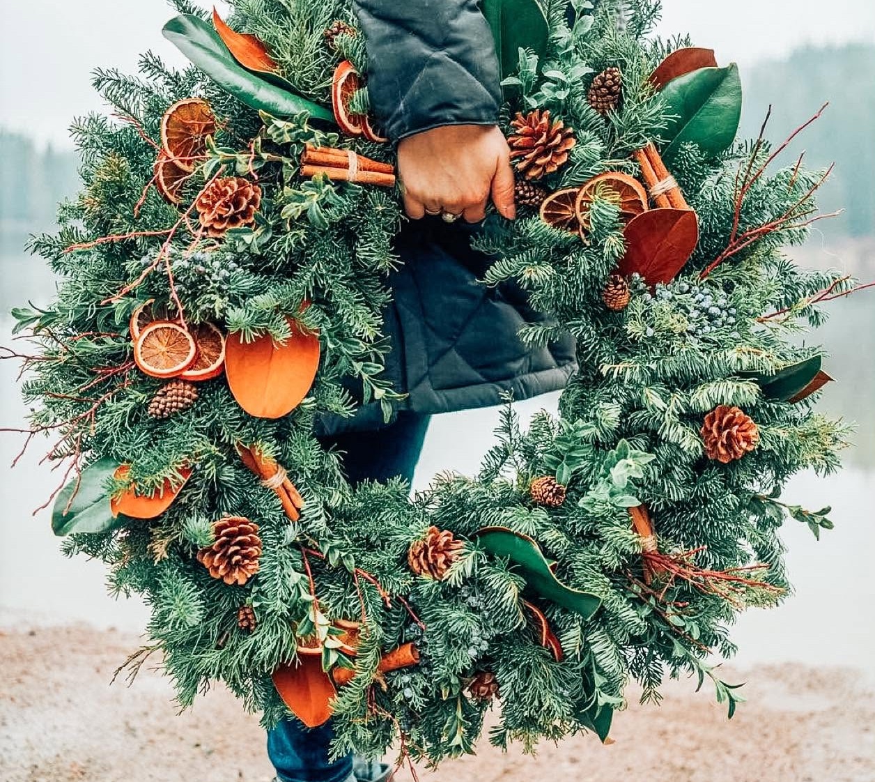Handcrafted holiday wreath with dried orange slices, pine cones, cinnamon sticks, and magnolia leaves