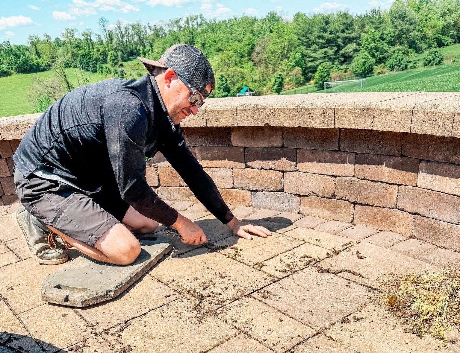Technician resetting and leveling existing paver stones