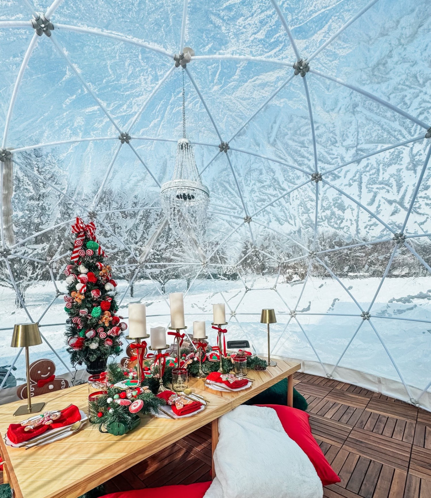 Luxury igloo with festive red and green Christmas tablescape and snowy winter view