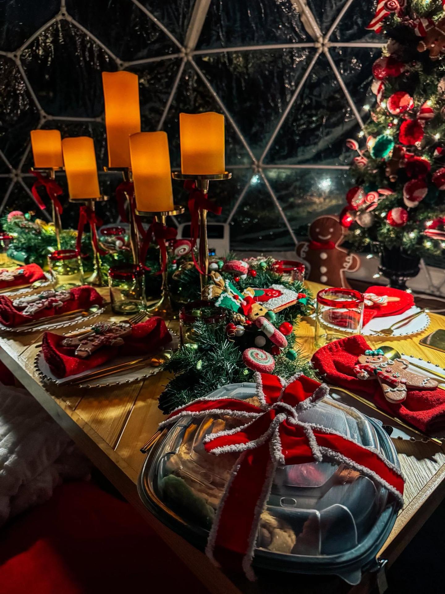 Candlelit holiday dinner inside a luxury igloo with decorated Christmas tree