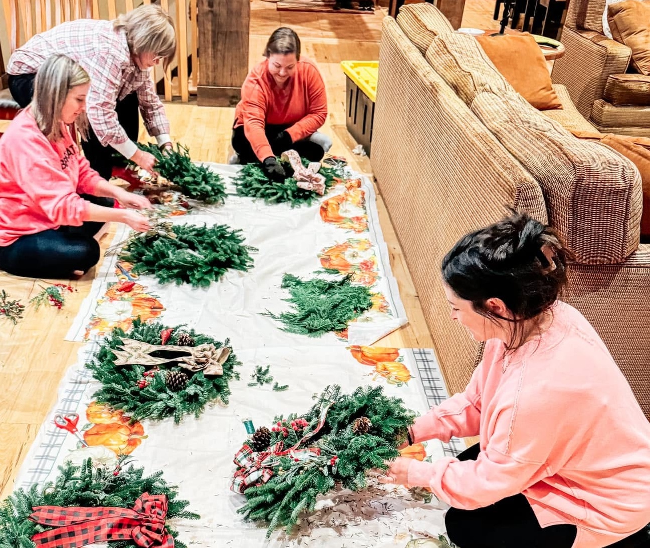 Group decorating fresh evergreen wreaths together at a private wreath workshop